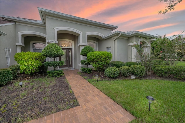 view of front of home featuring stucco siding and a front lawn