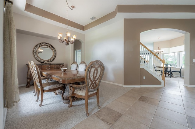 tiled dining area featuring a tray ceiling and an inviting chandelier