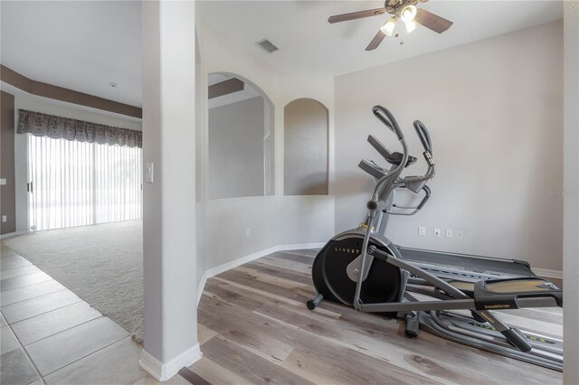 workout room with baseboards, visible vents, wood finished floors, and ceiling fan