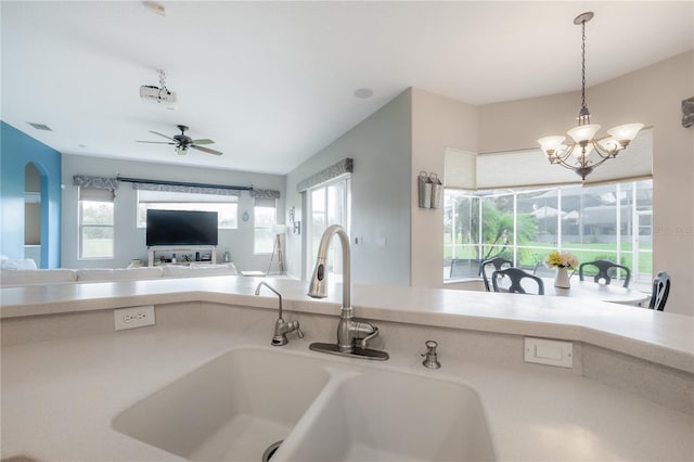 kitchen with ceiling fan with notable chandelier, sink, and pendant lighting