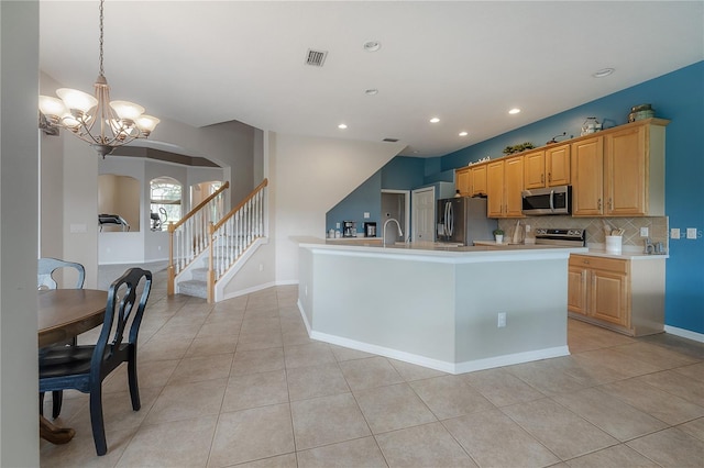 kitchen featuring light countertops, a chandelier, stainless steel appliances, arched walkways, and backsplash