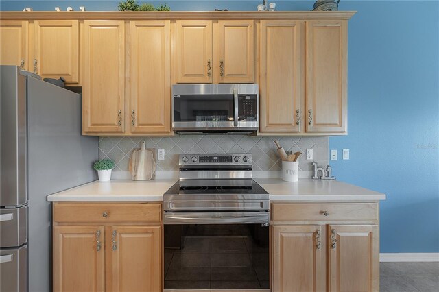 kitchen with appliances with stainless steel finishes, light brown cabinets, tasteful backsplash, and tile patterned floors