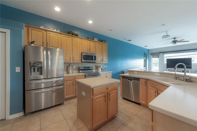 kitchen with light countertops, a sink, a ceiling fan, a kitchen island, and appliances with stainless steel finishes