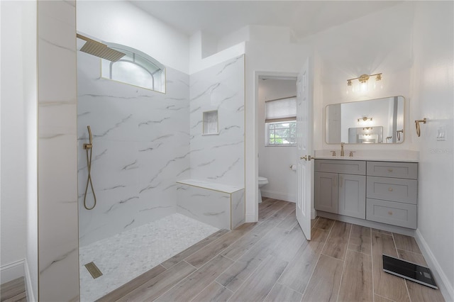 bathroom with baseboards, a marble finish shower, toilet, vanity, and wood tiled floor