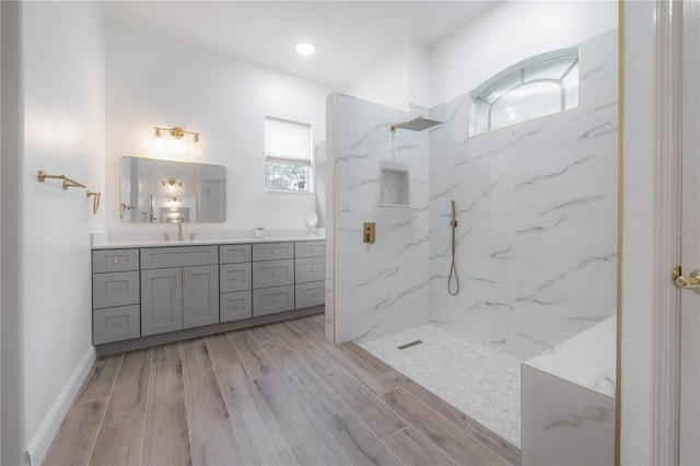 bathroom with a tile shower, vanity, and wood-type flooring