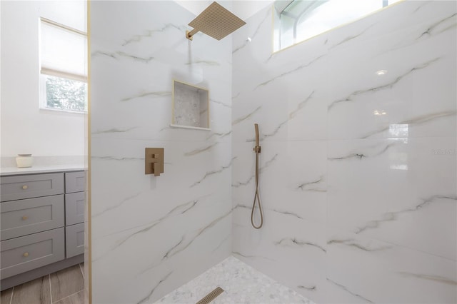 bathroom featuring hardwood / wood-style floors, a tile shower, and vanity