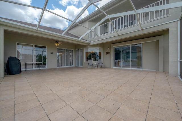 view of patio with ceiling fan, glass enclosure, and a balcony