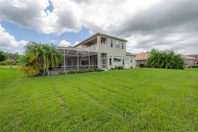 rear view of house with glass enclosure and a yard