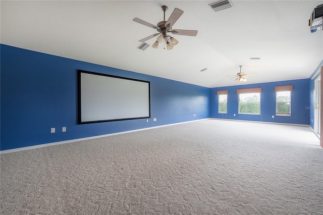 carpeted cinema room with baseboards, vaulted ceiling, visible vents, and a ceiling fan