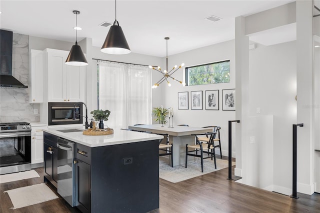 kitchen featuring appliances with stainless steel finishes, a kitchen island with sink, light countertops, white cabinetry, and a sink