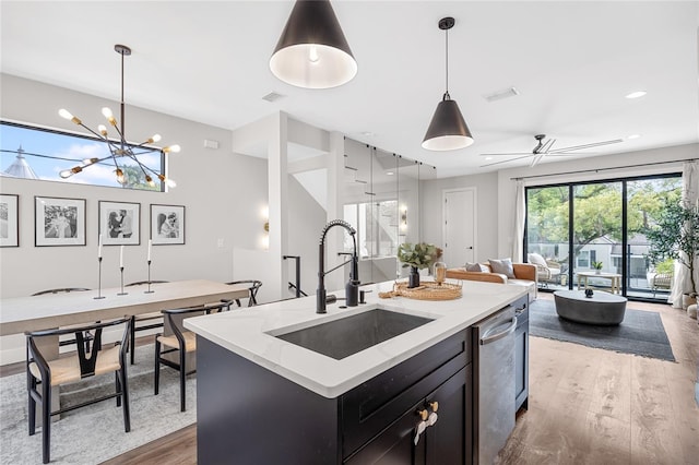 kitchen featuring decorative light fixtures, wood finished floors, a sink, open floor plan, and a center island with sink