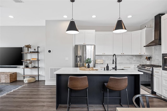 kitchen with stainless steel appliances, pendant lighting, a kitchen island with sink, and visible vents