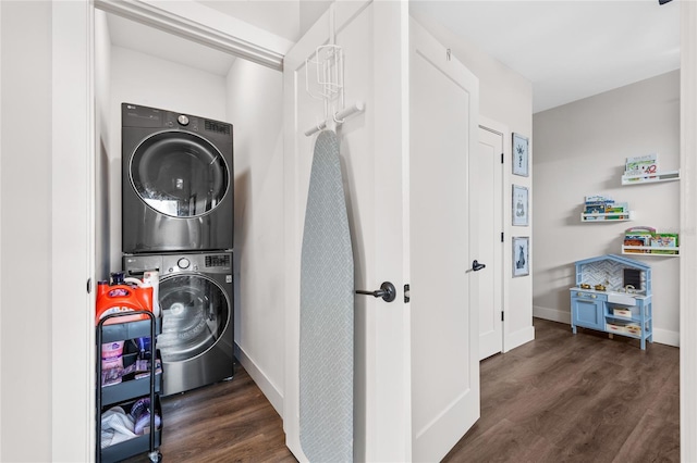 clothes washing area with dark wood-type flooring, laundry area, baseboards, and stacked washing maching and dryer