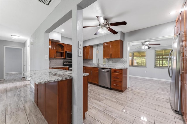 kitchen featuring appliances with stainless steel finishes, tasteful backsplash, light stone counters, kitchen peninsula, and ceiling fan