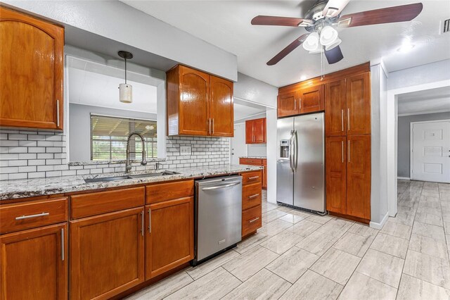 kitchen with appliances with stainless steel finishes, tasteful backsplash, sink, light stone counters, and ceiling fan