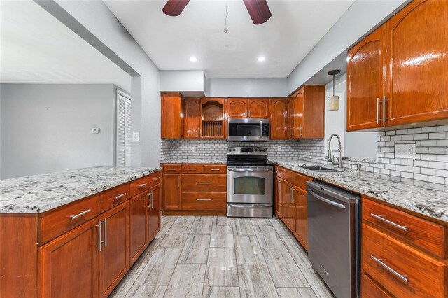 kitchen featuring sink, light stone counters, tasteful backsplash, ceiling fan, and stainless steel appliances