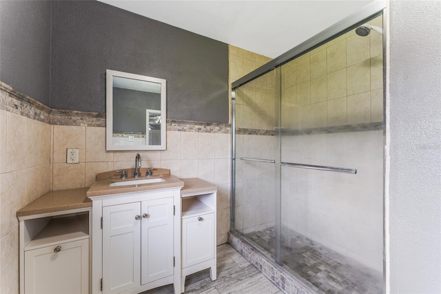 bathroom with tile patterned flooring, tile walls, an enclosed shower, and vanity