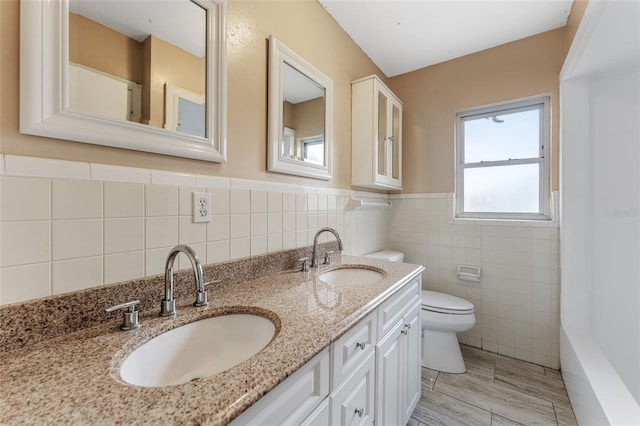 full bathroom with dual vanity, tasteful backsplash, toilet, and tile walls