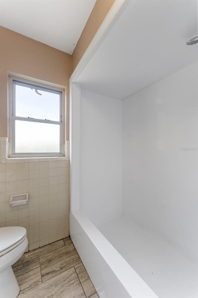 bathroom featuring tile walls,  shower combination, tile patterned floors, and toilet