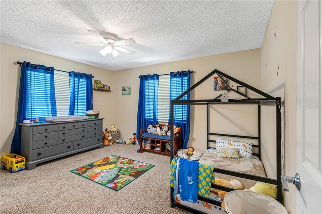 playroom with carpet floors, ceiling fan, and a textured ceiling