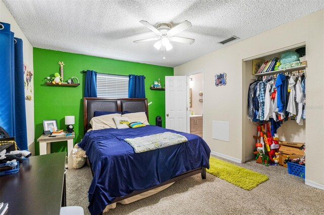 carpeted bedroom with a textured ceiling, a closet, ceiling fan, and ensuite bath