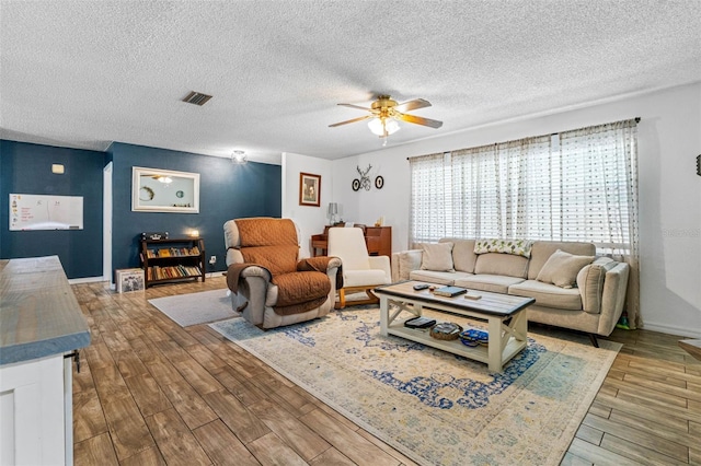 living room featuring ceiling fan, wood-type flooring, and a textured ceiling