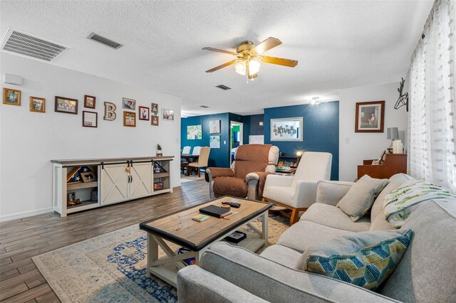 living room featuring ceiling fan, hardwood / wood-style flooring, and a textured ceiling