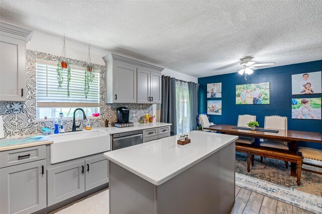 kitchen featuring tasteful backsplash, sink, a kitchen island, ceiling fan, and gray cabinets