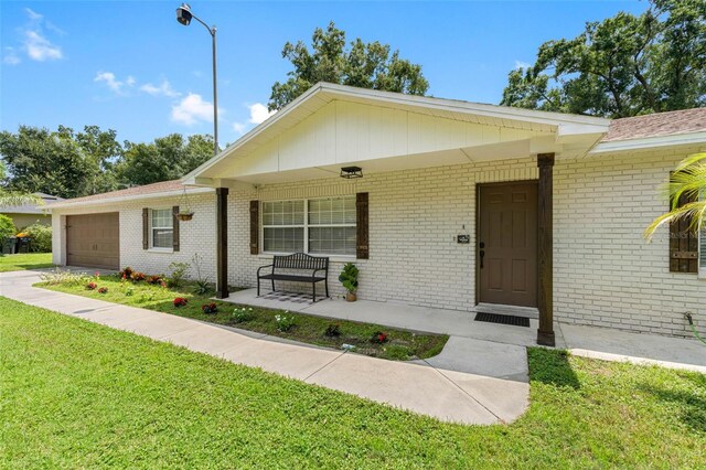 single story home with a porch, a front yard, and a garage