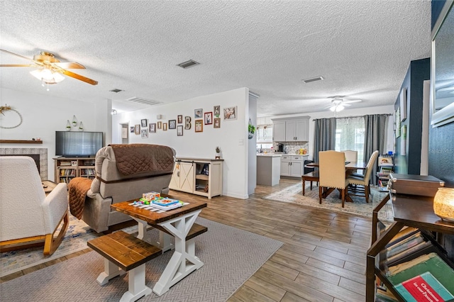 living room featuring hardwood / wood-style floors, ceiling fan, and a textured ceiling