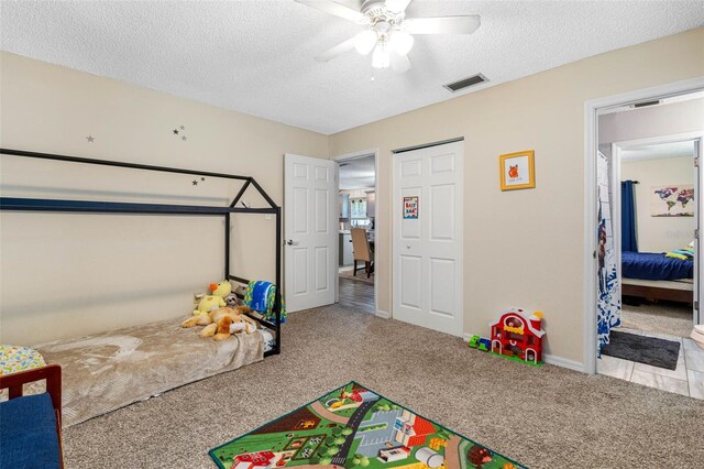 bedroom featuring light colored carpet, a textured ceiling, and ceiling fan