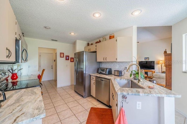 kitchen with kitchen peninsula, stainless steel appliances, sink, and decorative backsplash