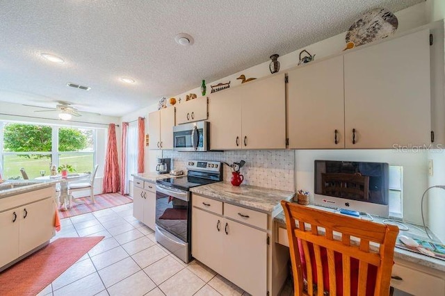 kitchen featuring a textured ceiling, stainless steel appliances, ceiling fan, and light tile patterned flooring