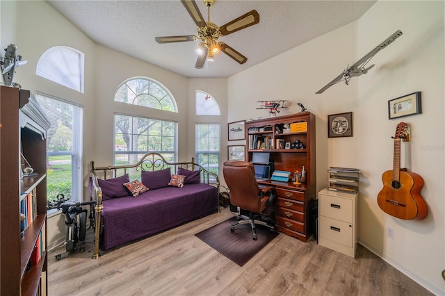 office space with a textured ceiling, ceiling fan, wood-type flooring, and a high ceiling