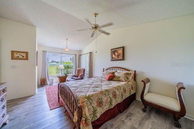 bedroom featuring a textured ceiling, vaulted ceiling, wood-type flooring, and ceiling fan