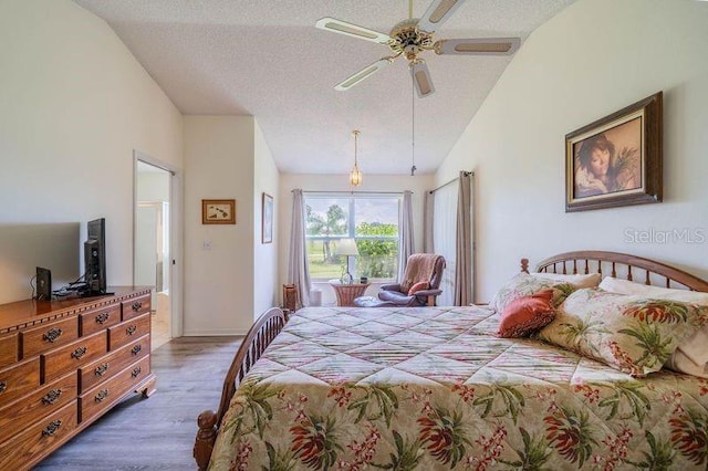 bedroom featuring ceiling fan, hardwood / wood-style flooring, a textured ceiling, and vaulted ceiling