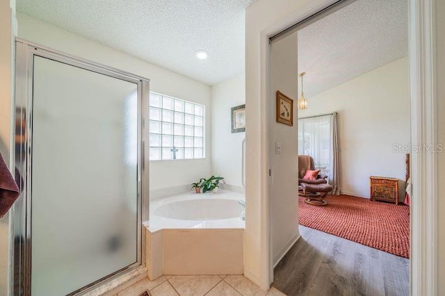 bathroom with independent shower and bath, a wealth of natural light, hardwood / wood-style flooring, and a textured ceiling