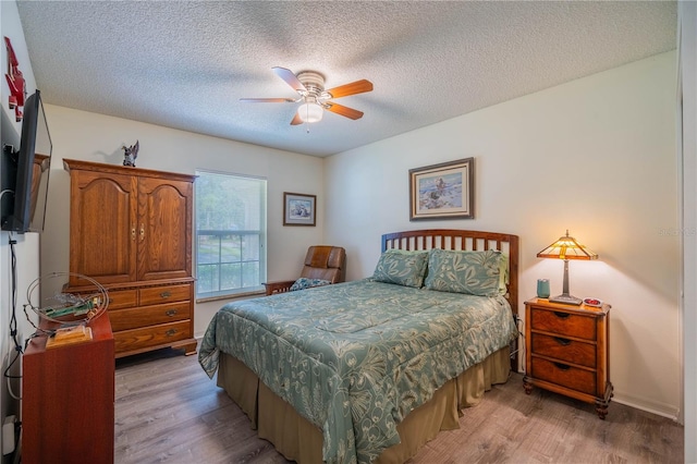 bedroom with a textured ceiling, ceiling fan, and light hardwood / wood-style floors