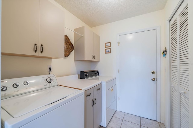 washroom featuring a textured ceiling, cabinets, washer and clothes dryer, and light tile patterned floors