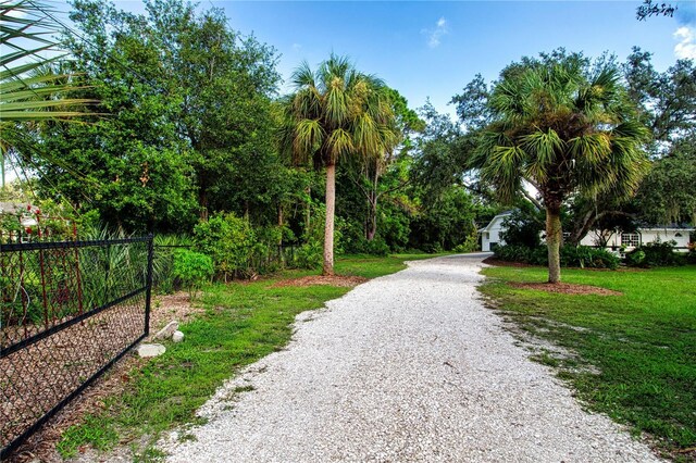 exterior space featuring gravel driveway, a yard, and fence