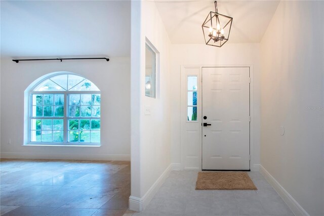 entrance foyer featuring light tile patterned floors, an inviting chandelier, and baseboards