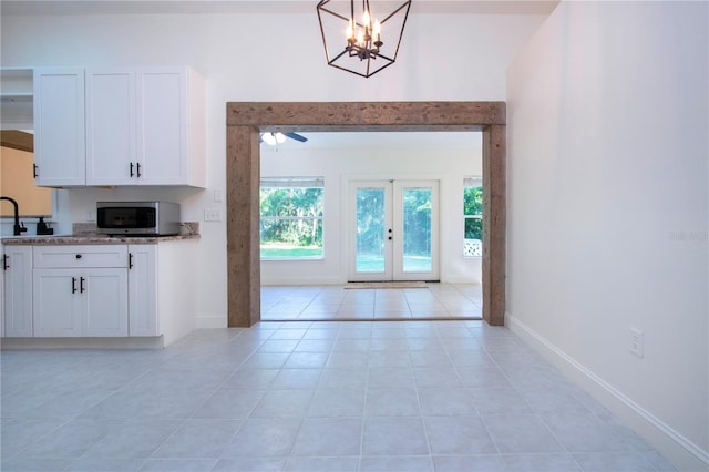 kitchen with white cabinetry, french doors, ceiling fan with notable chandelier, and light tile patterned floors