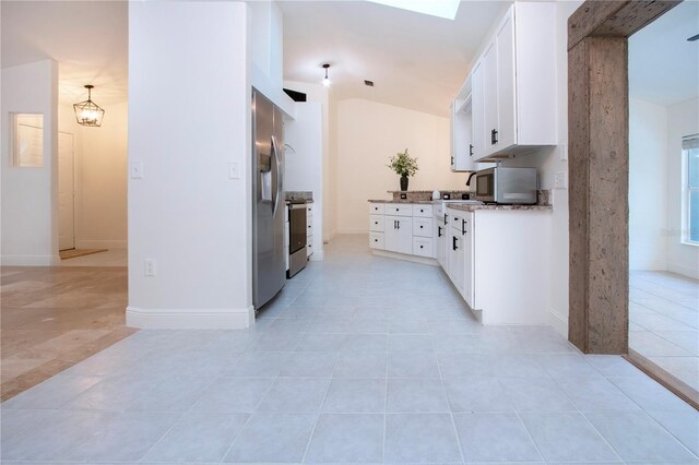 kitchen featuring light tile patterned floors, stainless steel appliances, white cabinets, light stone countertops, and baseboards