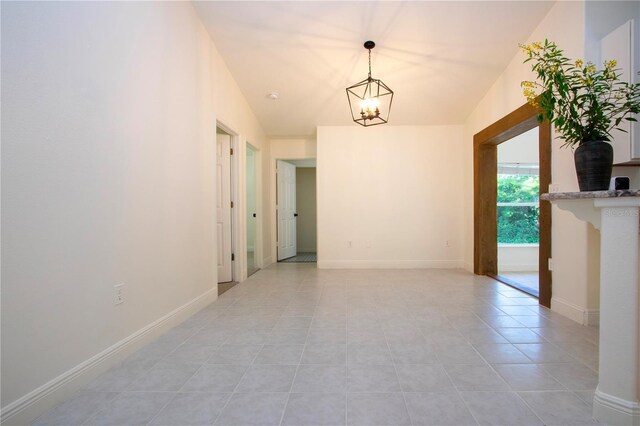 tiled spare room featuring an inviting chandelier