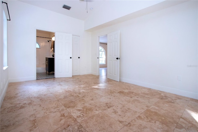 unfurnished bedroom featuring a closet, visible vents, a towering ceiling, connected bathroom, and baseboards