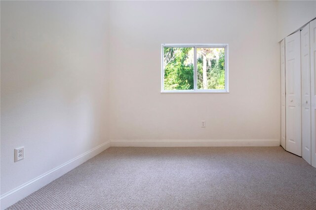 unfurnished bedroom with light carpet, baseboards, and a closet