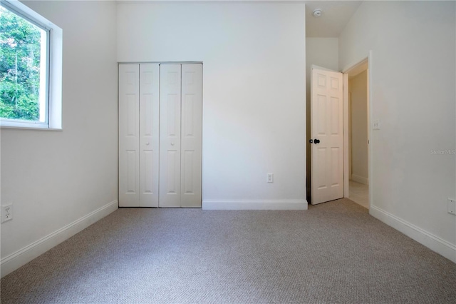 unfurnished bedroom featuring light colored carpet and a closet