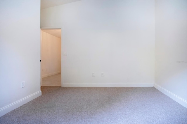 unfurnished room with vaulted ceiling and carpet flooring