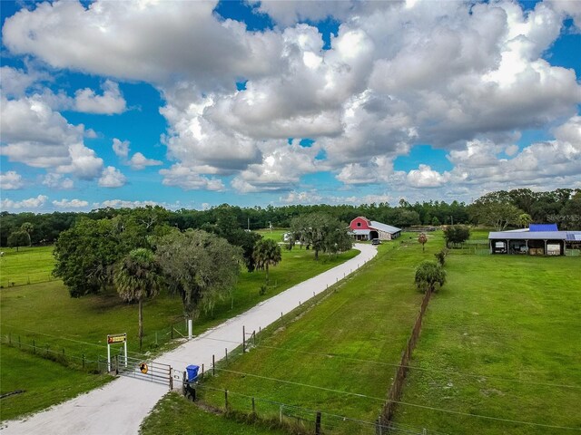 view of property's community with a gate, fence, a lawn, and a rural view