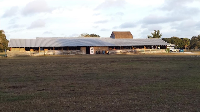 view of front facade featuring metal roof, an outdoor structure, an exterior structure, and a front yard